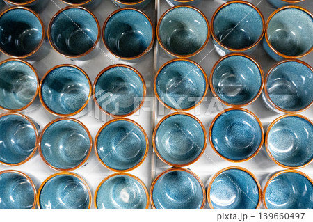 Blue cups and mugs in crockery shop, ceramic dishware, tableware stack in store Blue cups and mugs in crockery shop, ceramic dishware, tableware stack in store 139660497