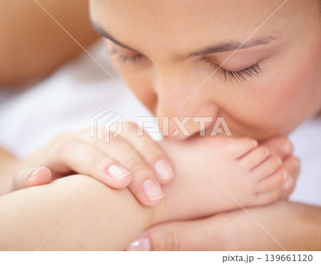 Mom, baby and kiss feet of child for love, care and relax in nursery room at home. Face, mother and closeup of foot of young kid for newborn development, healthy childhood growth or affection of bond 139661120