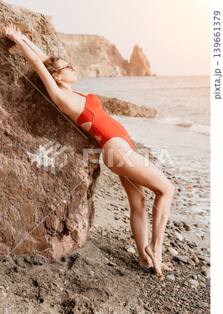 Woman beach swimsuit relax on a rocky seashore during summer vacation enjoying the ocean view and sunny weather Woman beach swimsuit relax on a rocky seashore during summer vacation enjoying the ocean view and sunny weather 139661379