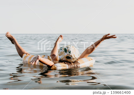 Woman Inflatable Ring Ocean - A woman enjoys a relaxing day at the beach, floating on an inflatable ring in the ocean. Woman Inflatable Ring Ocean - A woman enjoys a relaxing day at the beach, floating on an inflatable ring in the ocean. 139661400