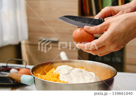 Hands prepare ingredients for meal in kitchen while cracking egg over bowl 139661840
