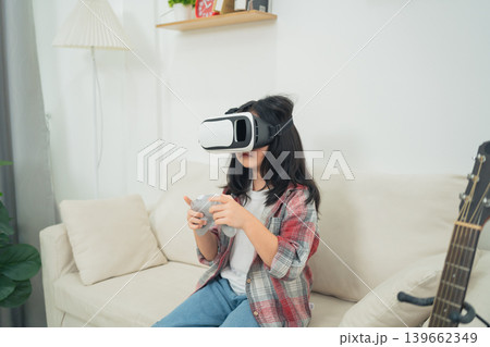 Young girl experiencing virtual reality gaming in a cozy living room environment with casual attire and modern home decor elements Young girl experiencing virtual reality gaming in a cozy living room environment with casual attire and modern home decor elements 139662349