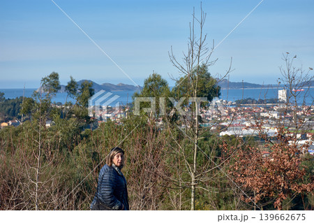 Woman standing on a mountain road in San Andres de Comesana, Vigo, with Vigo Bay behind Woman standing on a mountain road in San Andres de Comesana, Vigo, with Vigo Bay behind 139662675