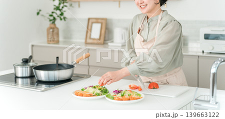 キッチンで料理をするエプロン姿の若いアジア人女性 キッチンで料理をするエプロン姿の若いアジア人女性 139663122