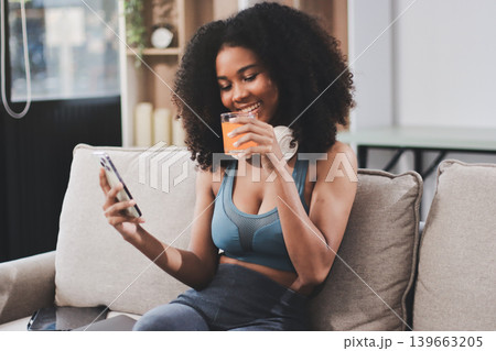 Young nutritionist showing bell peppers during an online video call consulting about healthy eating, sitting at home at a table with vegetables, laptop and measuring tape 139663205