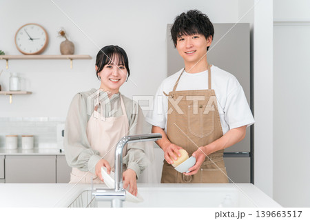 マイホームのキッチンで一緒に家事・お皿洗いををしながら会話する仲良しのアジア人夫婦の男女 マイホームのキッチンで一緒に家事・お皿洗いををしながら会話する仲良しのアジア人夫婦の男女 139663517