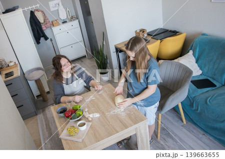 Lifestyle portrait of child girl preparing dough with her mother at home Lifestyle portrait of child girl preparing dough with her mother at home 139663655