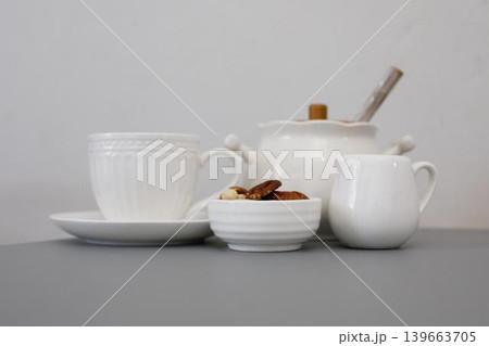 Teacups and snack bowl on a gray table with a teapot and creamer at a quiet afternoon tea setting 139663705