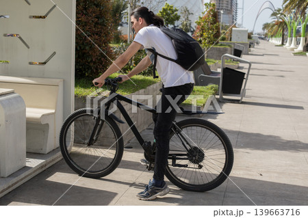 A person rides a bicycle along a pathway in a busy city. A person rides a bicycle along a pathway in a busy city. 139663716