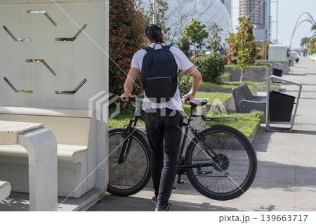 A person rides a bicycle along a pathway in a busy city. A person rides a bicycle along a pathway in a busy city. 139663717