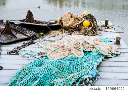 Fishing nets and ropes on wooden dock near water Fishing nets and ropes on wooden dock near water 139664022