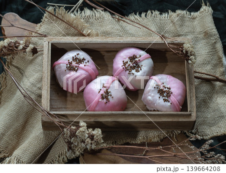 our Strawberry Cream Cheese Mochi reimagines a classic treat with artisanal flair. Presented in a traditional wooden tray and accented with crisp toasted toppings, these soft, pillowy bites offer a 139664208