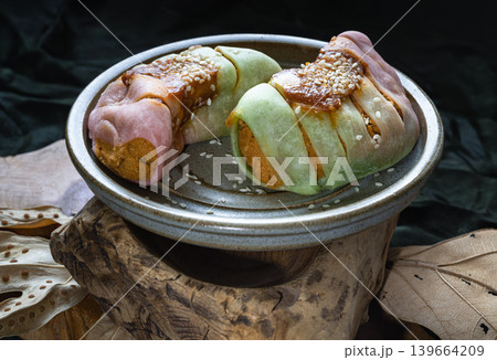 This beautifully presented dish features artisanal, multi-colored roll buns filled with savory chicken floss, lightly glazed with spicy chili paste and a delicate dusting of sesame seeds, all 139664209