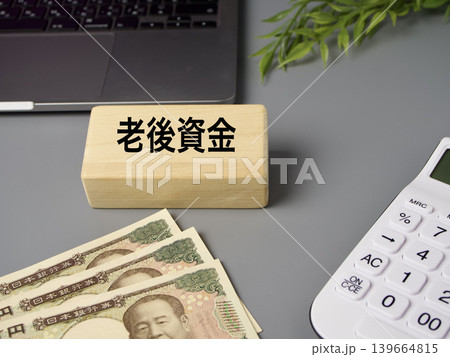 老後資金をイメージした木製ブロックと電卓と紙幣の金融イメージ グレー背景 老後資金をイメージした木製ブロックと電卓と紙幣の金融イメージ グレー背景 139664815