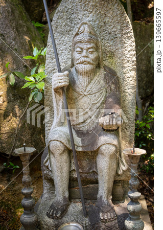 Ancient stone statue with staff on Miyajima Island, Japan Ancient stone statue with staff on Miyajima Island, Japan 139665597