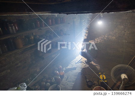 Person welding in dimly lit basement with tools and storage Person welding in dimly lit basement with tools and storage 139666274
