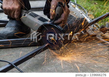Metalworking with Angle Grinder Sparks Flying Outdoors 139666276