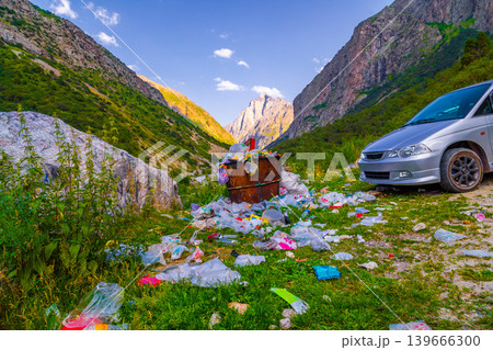 Overflowing garbage can in natural landscape with minivan 139666300