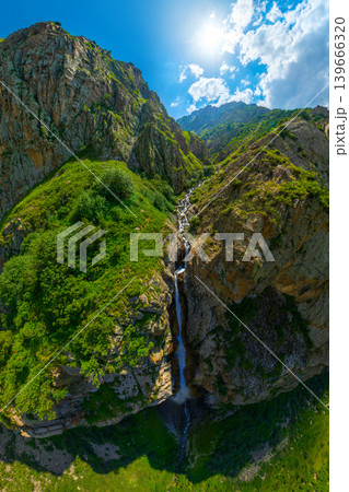 Aerial view of mountain waterfall in lush green gorge 139666320