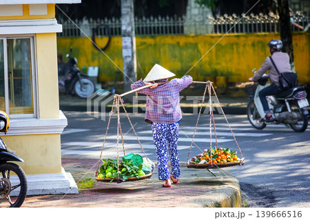 Traditional Vietnamese street vendor carrying baskets with tropical fruits in Ho Chi Minh City, Vietnam. Traditional Vietnamese street vendor carrying baskets with tropical fruits in Ho Chi Minh City, Vietnam. 139666516