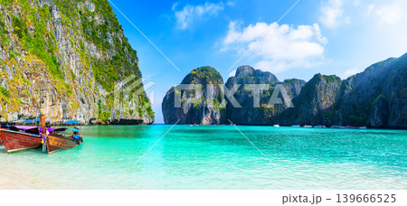 Wide Tropical Beach Scene in Maya Bay, Phi Phi islands in Thailand. Panoramic view of sandy beach with longtail boat and turquoise lagoon in Maya Bay in Thailand, ideal for banners and high-end travel Wide Tropical Beach Scene in Maya Bay, Phi Phi islands in Thailand. Panoramic view of sandy beach with longtail boat and turquoise lagoon in Maya Bay in Thailand, ideal for banners and high-end travel 139666525
