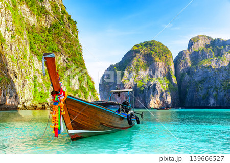 Longtail Boat in Maya Bay Lagoon, Phi Phi islands in Thailand. Tropical scenery of Maya Bay with traditional longtail boat, turquoise water and dramatic limestone cliffs Longtail Boat in Maya Bay Lagoon, Phi Phi islands in Thailand. Tropical scenery of Maya Bay with traditional longtail boat, turquoise water and dramatic limestone cliffs 139666527