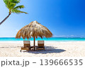 Sunny tropical beach with lounge chairs and palm umbrella in Punta Cana, Dominican republic. Perfect vacation destination with white sand, turquoise ocean and clear blue sky. 139666535