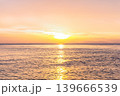 Peaceful sunset over the ocean with soft golden light reflecting on calm water. 139666539