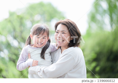 新緑の公園で母親に抱きつく笑顔の女の子 親子愛と幸せな家族時間　ママ大好き～母の日や幸せなイメージ	 139666812