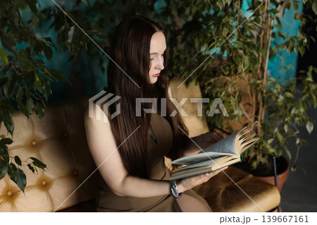 Solitary figure with flowing hair deeply engaged in reading comfort Solitary figure with flowing hair deeply engaged in reading comfort 139667161