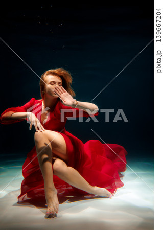 Underwater escape artist wearing scarlet outfit surges upward with energy 139667204