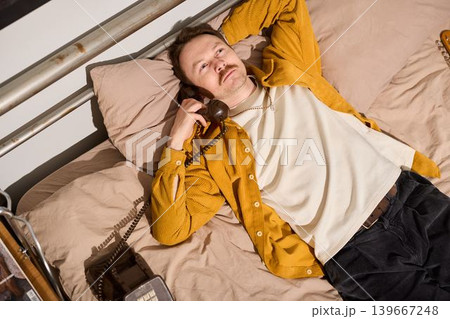 Artist relaxes on bed surrounded by musical tools and soft lamp glow Artist relaxes on bed surrounded by musical tools and soft lamp glow 139667248