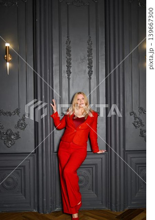Stylish lady in red. Selfassured woman against ornate vintage wall setting Stylish lady in red. Selfassured woman against ornate vintage wall setting 139667300