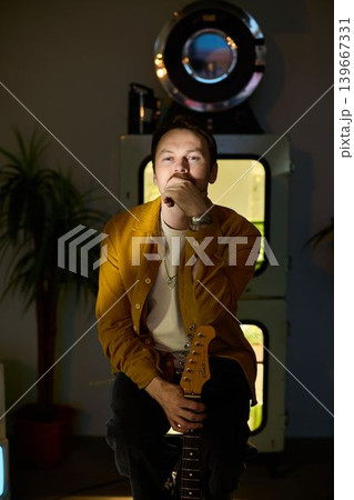 Man with vintage television glow pauses in musical reflection 139667331