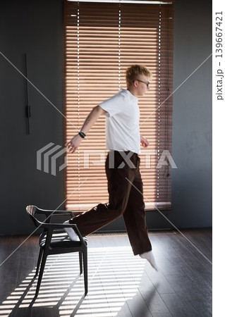 Dynamic leap above chair amidst vivid shadows and illumination Dynamic leap above chair amidst vivid shadows and illumination 139667421