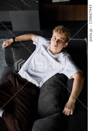 Fashionably dressed young man relaxing on sofa in urban studio apartment Fashionably dressed young man relaxing on sofa in urban studio apartment 139667443