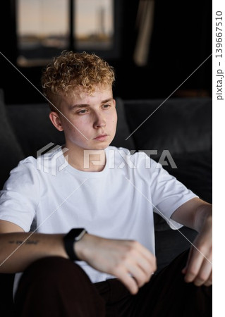 Pensive young man enjoys tranquil moment inside warmly lit modern home 139667510