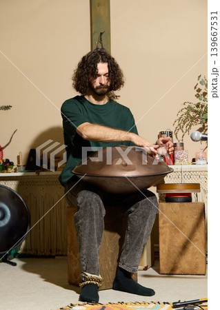Informal home recording of man playing handpan with beverage and keyboard Informal home recording of man playing handpan with beverage and keyboard 139667531
