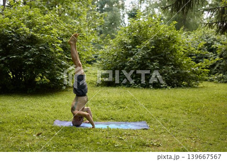 Individual maintains headstand position amidst vibrant park surroundings Individual maintains headstand position amidst vibrant park surroundings 139667567