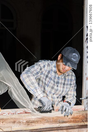 Dedicated craftsman carefully restoring weathered window with precision 139667608
