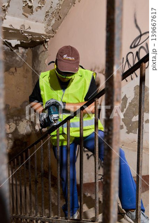 Construction worker focused on grinding metal amidst dusty surroundings 139667617