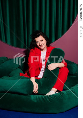 Lady dressed in crimson hugging soft pillow with gentle smile 139667675