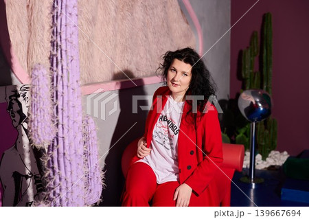 Confident woman dressed in red smiling among vibrant decorative items Confident woman dressed in red smiling among vibrant decorative items 139667694