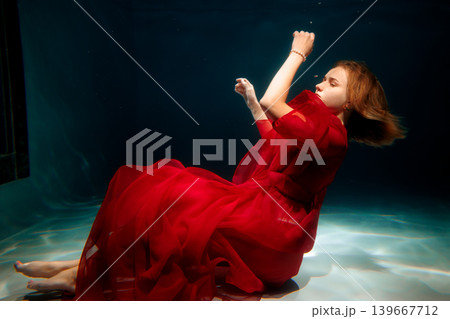 Underwater scene featuring calm caucasian woman with red hair Underwater scene featuring calm caucasian woman with red hair 139667712