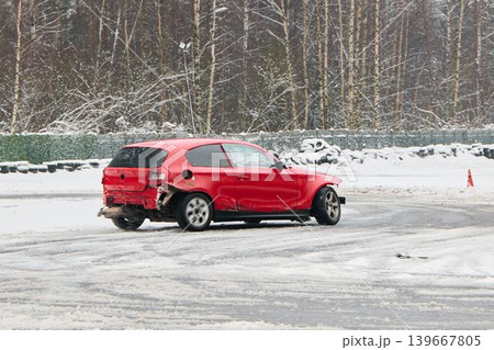 Red vehicle maneuvering through cones during winter autocross event 139667805