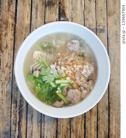 Hot pork and shiitake mushroom rice porridge on a wooden table, cozy Asian comfort food. Hot pork and shiitake mushroom rice porridge on a wooden table, cozy Asian comfort food. 139667904