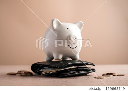 Piggy bank on wallet with cash and coins, savings personal finance wealth management and budgeting concept Piggy bank on wallet with cash and coins, savings personal finance wealth management and budgeting concept 139668349
