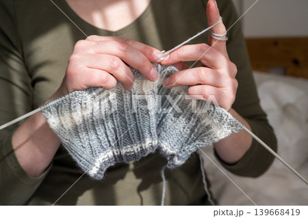 Woman knitting, close-up hands with yarn and knitted scarf. Handicraft hobby concept 139668419