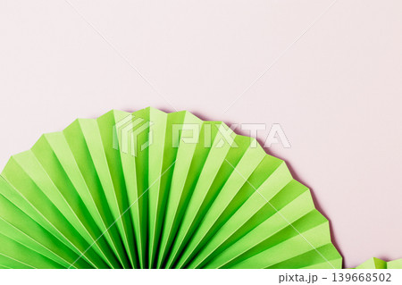 Minimalist green fan against pastel pink background 139668502