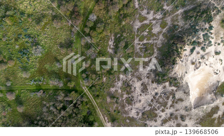 Top-down aerial view of coastal sand dunes covered in green scrub vegetation. Natural texture pattern of a dune landscape with animal tracks and small footprints in the sand. Top-down aerial view of coastal sand dunes covered in green scrub vegetation. Natural texture pattern of a dune landscape with animal tracks and small footprints in the sand. 139668506